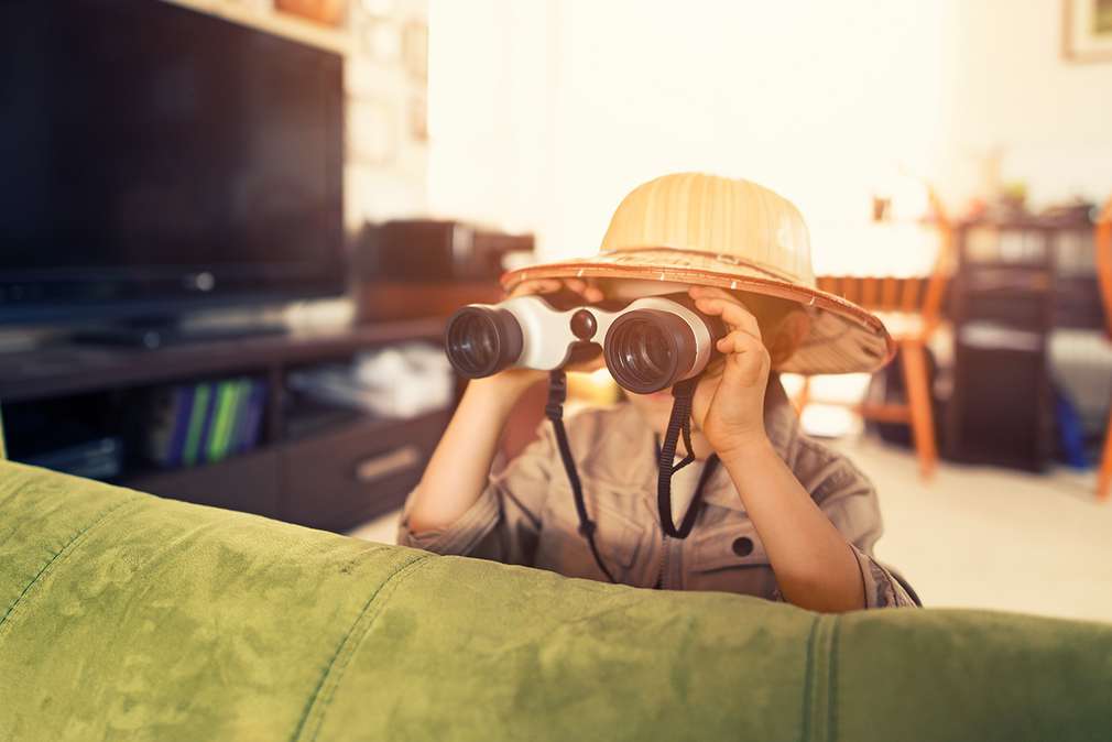 Изображение на дете, което, маскирано като изследовател, наблюдава през бинокъл.