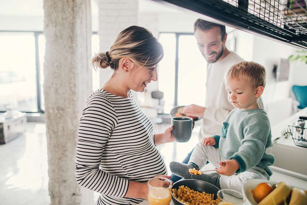 Изображение на младо семейство с малко дете, което се приготвя за закуска в кухнята