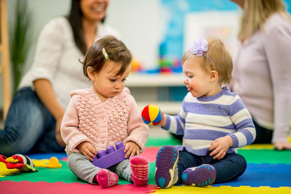 Изображение на две малки деца, които си играя, седнали на пода