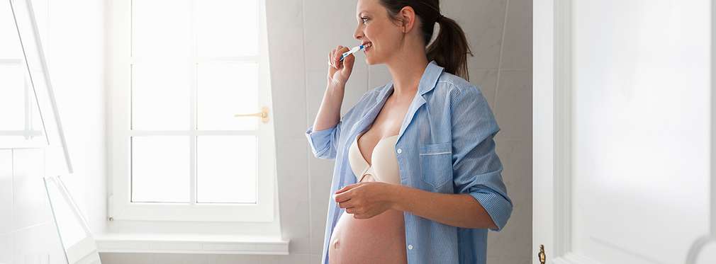 Изображение на бременна жена, която си мие зъбите