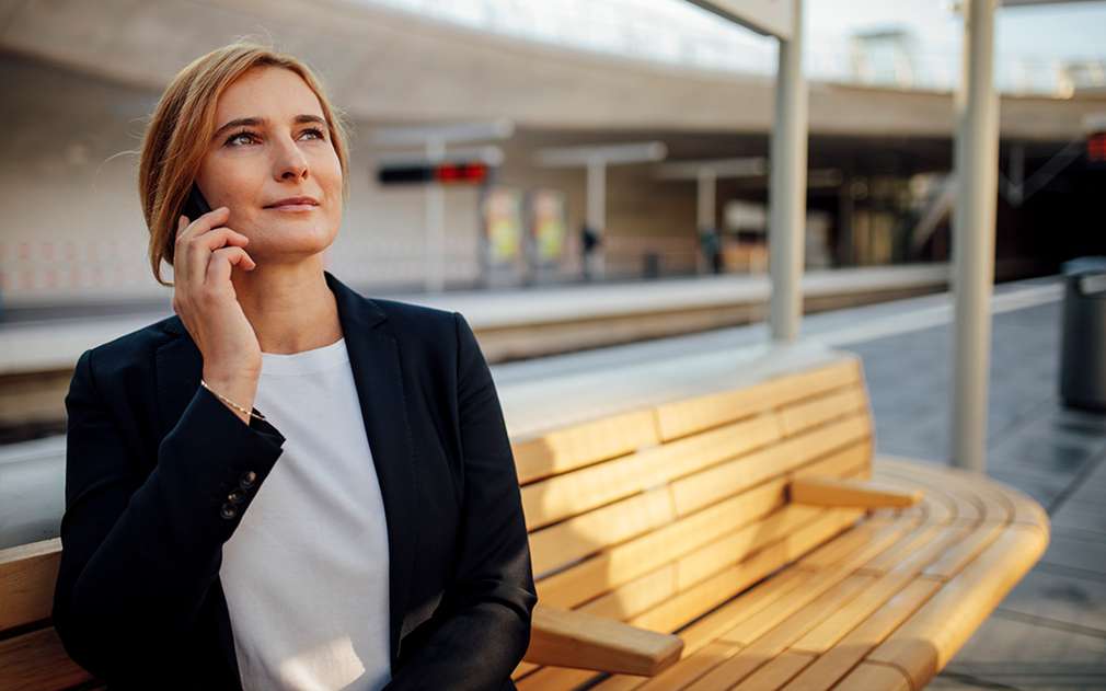Žena sedí na lavičce a telefonuje Žena sedí na lavičce a telefonuje