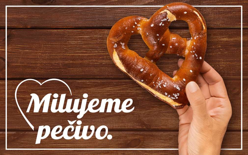 Milujeme pečivo. Mužská ruka drží preclík ve tvaru srdce