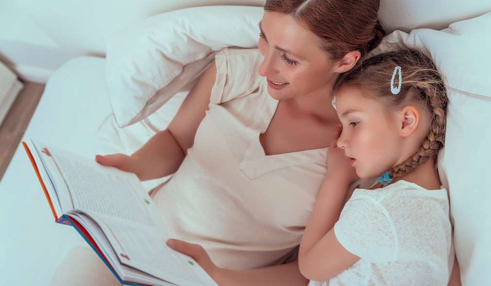 Mutter liest Tochter aus einem Buch vor Mutter liest Tochter aus einem Buch vor