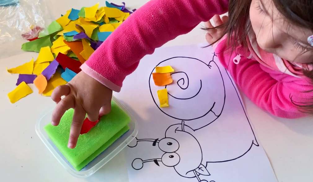 Mädchen bastelt ein buntes Bild aus Papierschnipseln Mädchen bastelt ein buntes Bild aus Papierschnipseln