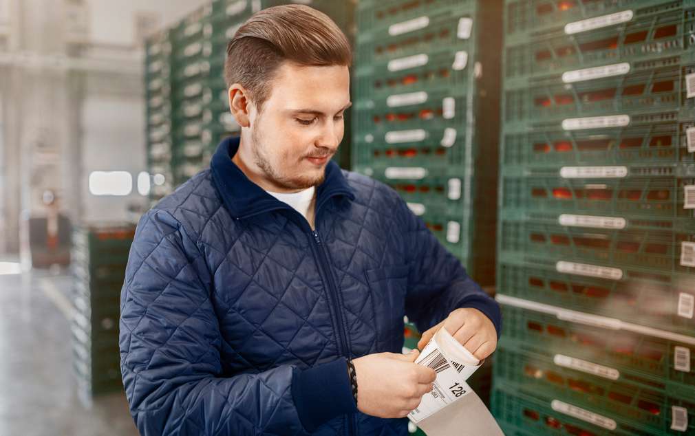 Auszubildender in der Logistik nimmt Ware entgegen und prüft diese Auszubildender in der Logistik nimmt Ware entgegen und prüft diese