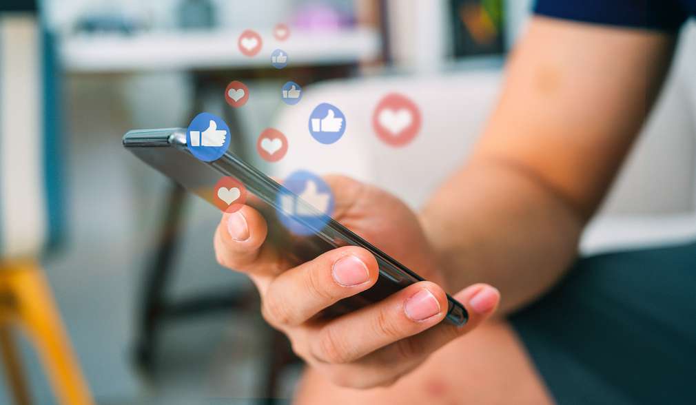 Mann hält Smartphone in der Hand über dem Like-Icons schweben Mann hält Smartphone in der Hand über dem Like-Icons schweben