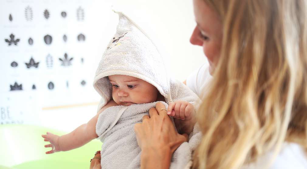 Mama wickelt Baby in Kapuzenhandtuch ein Mama wickelt Baby in Kapuzenhandtuch ein