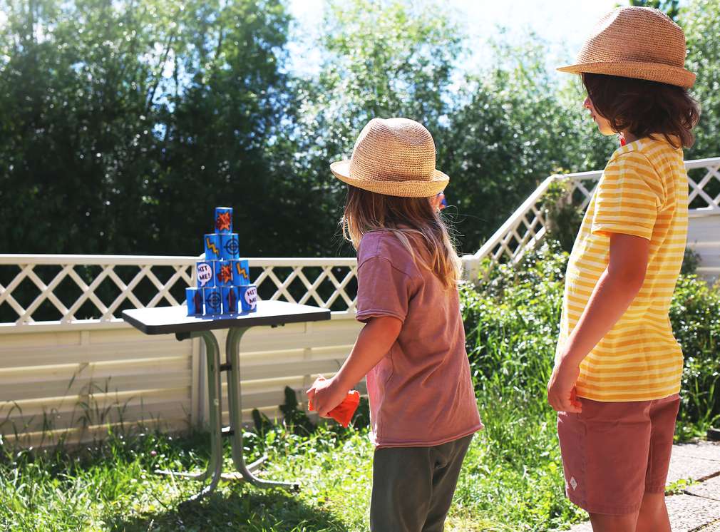 Zwei Kinder im Garten beim Dosenwerfen Zwei Kinder im Garten beim Dosenwerfen