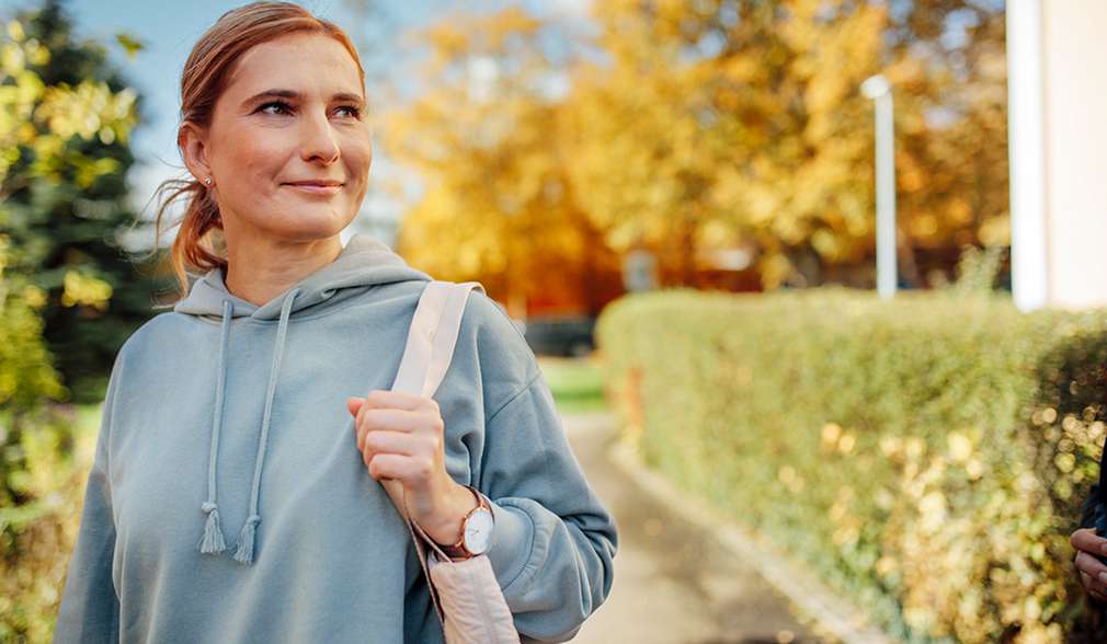 Frau mit Tasche auf der Schulter blickt nach rechts Frau mit Tasche auf der Schulter blickt nach rechts
