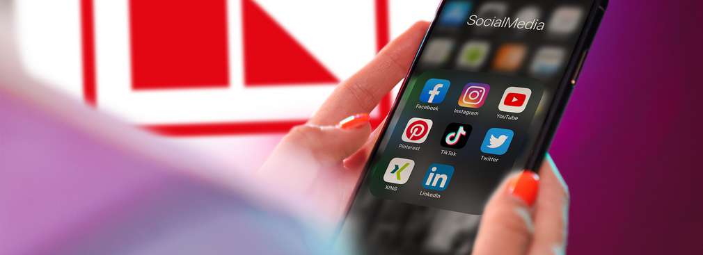 Kobieta trzyma w ręce smartfona z ekranem, na którym widać ikonki aplikacji mediów społecznościowych