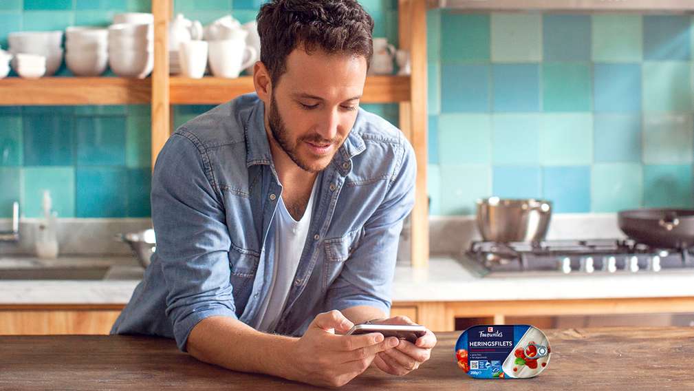 Muž si hledá informace o zboží na mobilním telefonu